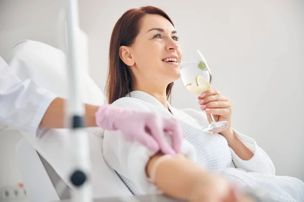 Atractiva mujer morena sonriendo durante la terapia intravenosa — Foto de Stock