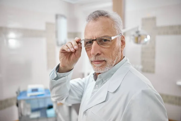 Professional dentist proudly posing in his dental clinic — Stock Photo, Image