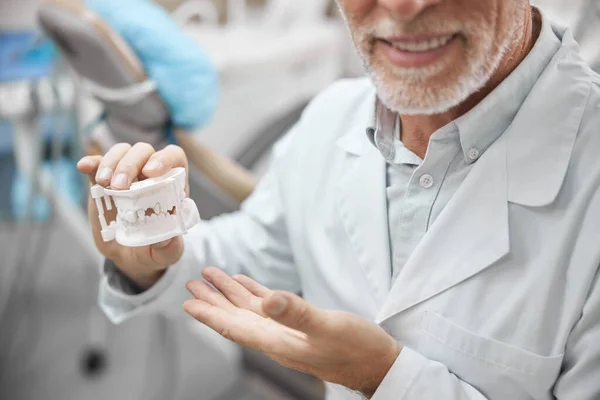 Odontólogo anciano mostrando un modelo de yeso de dientes — Foto de Stock