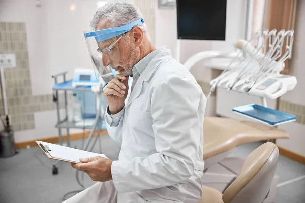 Yaşlı dişçi randevularını kontrol ediyor. — Stok fotoğraf