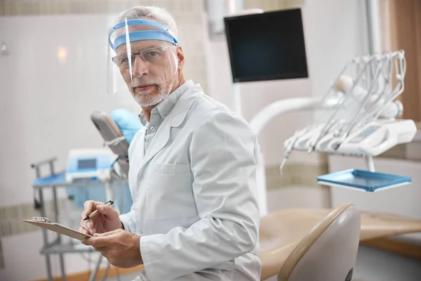 Specialista dentale competente che prende appunti sul lavoro — Foto Stock