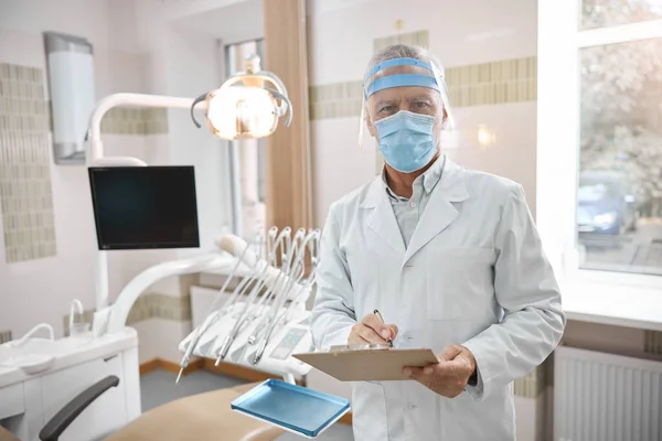 Képzett fogorvos, aki egy tabletta képernyőjét nézi. — Stock Fotó