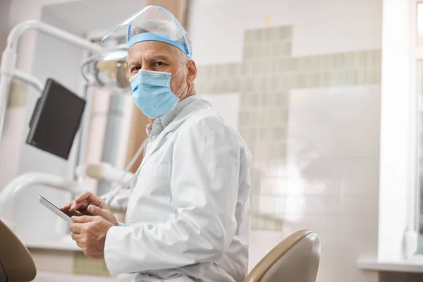 Профессиональный старший стоматолог держит планшет — стоковое фото