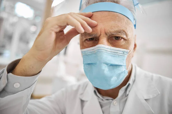 Aged healthcare worker wearing a protective mask — Stock Photo, Image