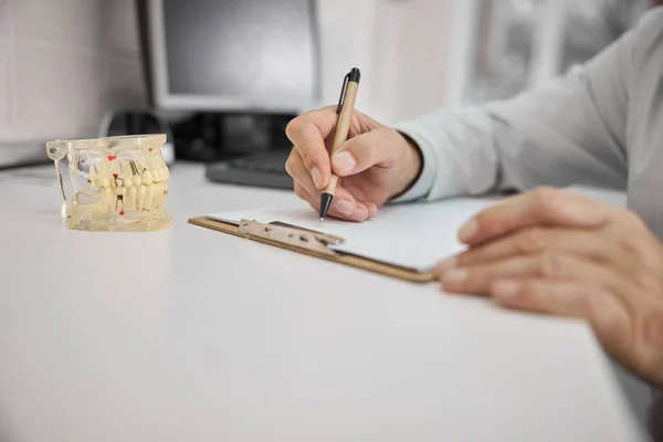 Dentista escribiendo una receta para implante dental — Foto de Stock