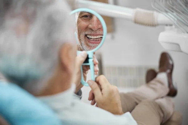 Eldelry hombre mirando en el espejo y sonriendo — Foto de Stock