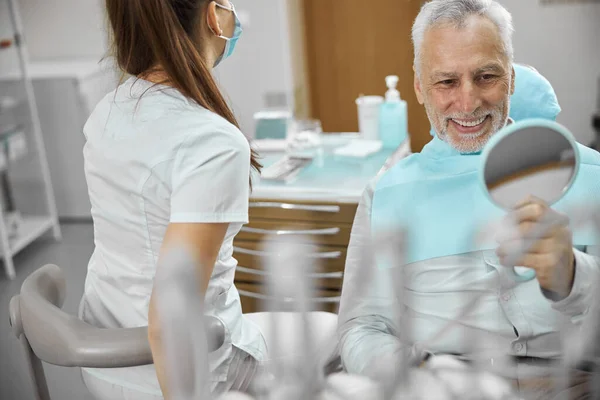 Gladsome äldre patient ler mot tandläkare kontor — Stockfoto