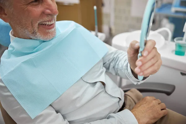 Eldelry pacient se dívá na své zuby v zrcadle — Stock fotografie