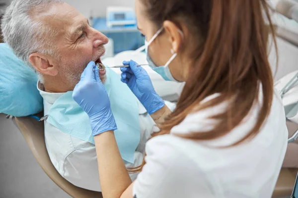 Kompetente Zahnärztin untersucht einen älteren Mann — Stockfoto