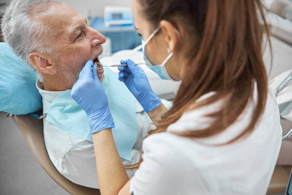 Competent female dentist examining an elderly man