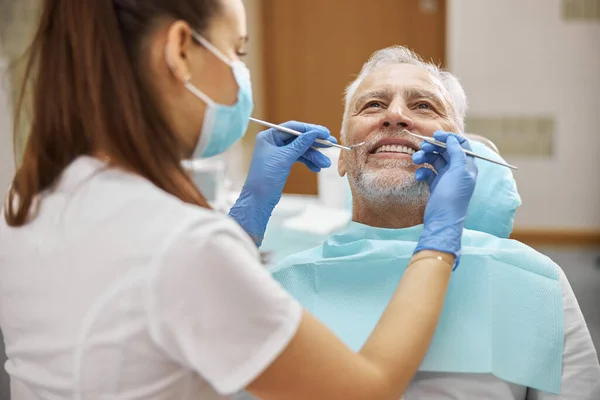 Tandheelkundige specialist die tanden van een bejaarde onderzoekt — Stockfoto