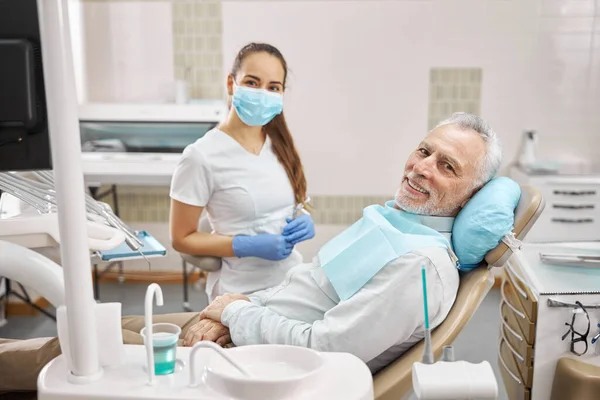 Ung tandläkare och äldre patient ser glad på kliniken — Stockfoto