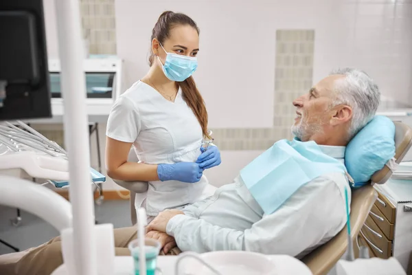 Přátelský ženský zubař při pohledu na svého staršího pacienta — Stock fotografie