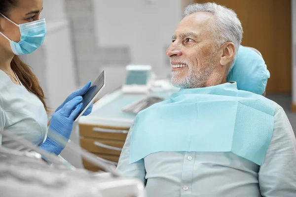 Eldelry medborgare sitter i en tandläkarstol nära sin tandläkare — Stockfoto