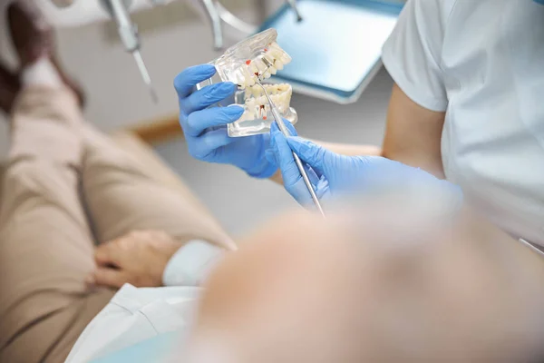 Dentista demostrando prótesis dentales de mandíbula completa a un paciente — Foto de Stock
