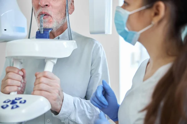 Experta dental femenina preparando a un anciano para rayos X dentales — Foto de Stock