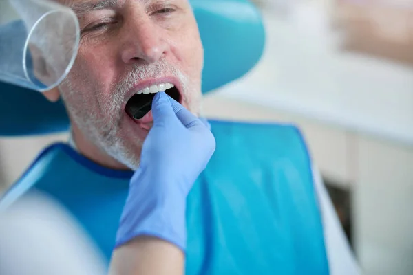 Especialista dental poniendo una tarjeta de película dentro de la boca de un paciente —  Fotos de Stock