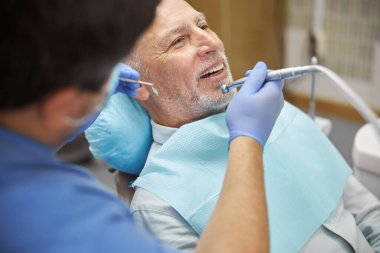 Gladsome yaşIı adam dişlerini diş kliniğinde tedavi ettiriyor.
