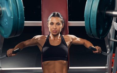 Göğüs presi makinesinde spor yapan atletik bir kadın.