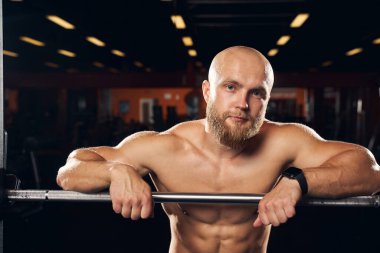 Spor salonunda üstsüz duran kaslı adam.