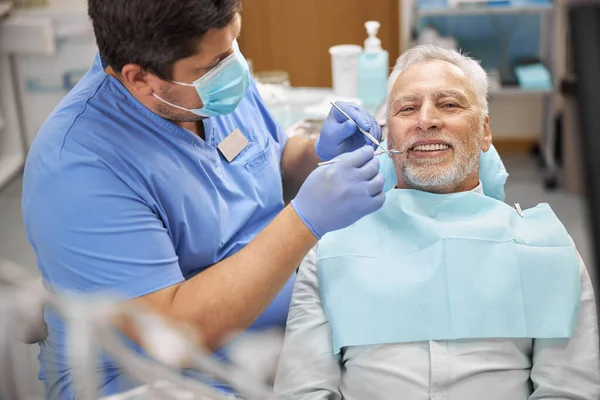 Oudere patiënt die een tandheelkundige behandeling krijgt in de kliniek — Stockfoto