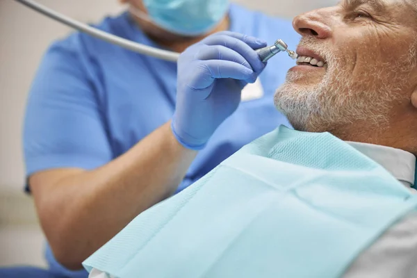 Dentiste qualifié travaillant avec un brunisseur dentaire — Photo