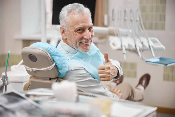 Dentistas pacientes sentados en una silla dental mostrando los pulgares hacia arriba — Foto de Stock