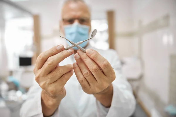 Dentista professionista tenendo i suoi strumenti dentali incrociati — Foto Stock