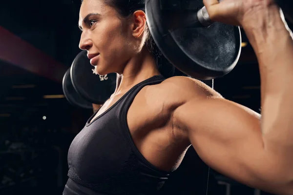 Vastberaden jonge vrouw aan het sporten in de sportschool — Stockfoto