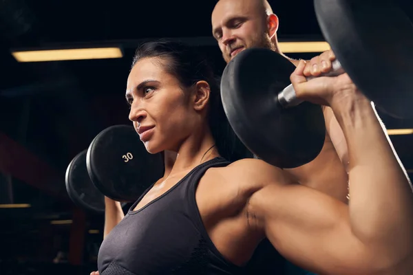 Strong female working out at the gym with her partner