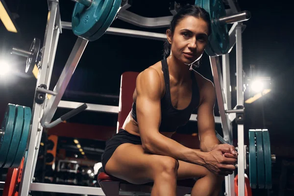 Gespierde vrouw zittend aan het stuk van de sportschool apparatuur — Stockfoto