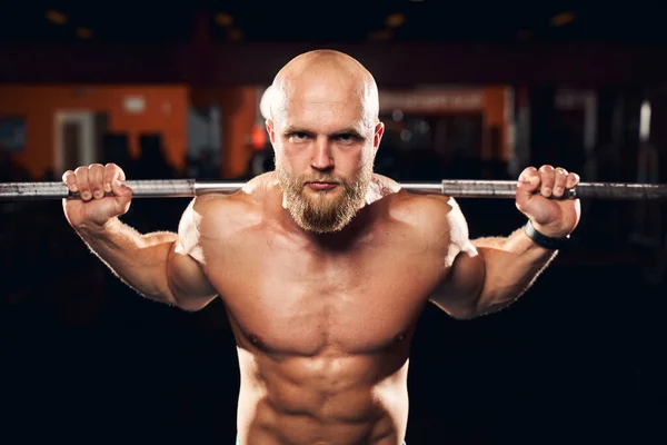 Hombre bien construido haciendo ejercicio con una barra en el gimnasio —  Fotos de Stock