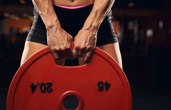 Güçlü bayan sporcu ağırlık plakasıyla egzersiz yapıyor. — Stok fotoğraf