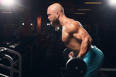 Spor salonunda çalışan kaslı bir adam.