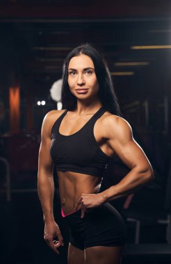 Kadın vücut geliştirici kaslarını esneterek gücünü gösteriyor.