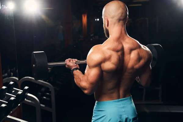 Strong muscly man wearing no shirt and lifting weights — Stock Photo, Image