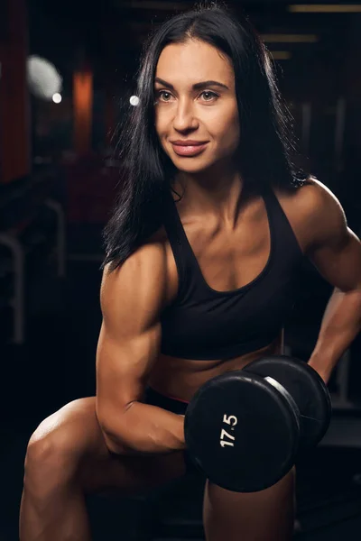 Encantadora atleta femenina sosteniendo una mancuerna en el gimnasio — Foto de Stock