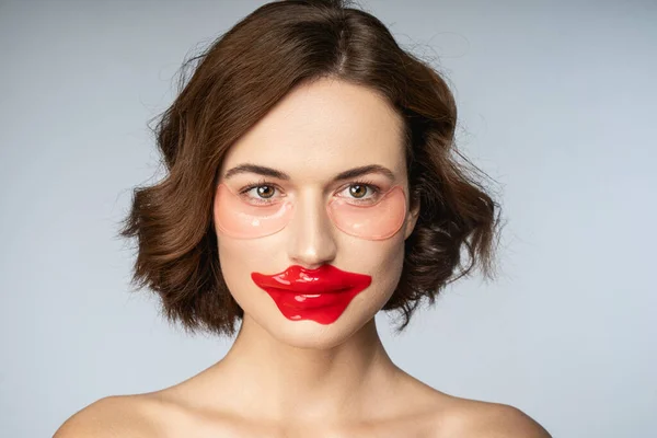 Чарівна молода жінка використовує колагенну губну пляму і латки під очима — стокове фото