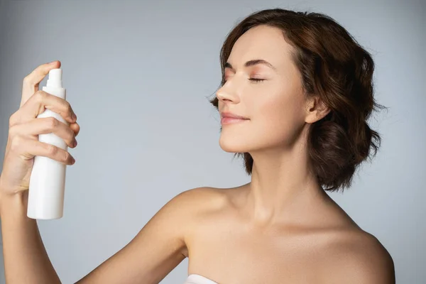 Hermosa joven sosteniendo botella de spray cosmético — Foto de Stock