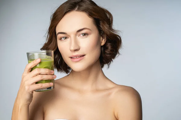 Beautiful young woman holding glass of smoothie — Stock Photo, Image