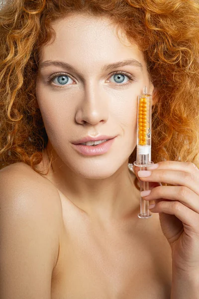 Schöne junge Frau hält Spritze mit Goldserum — Stockfoto