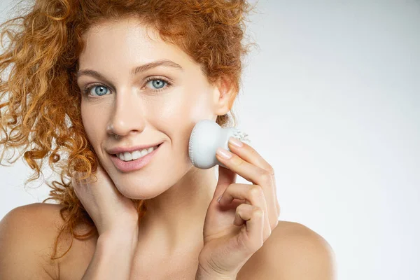 Beautiful young woman using facial cleaning massage brush — Stock Photo, Image