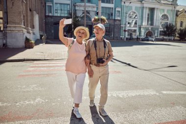 Dışarıda selfie çeken iki neşeli yaşlı turist.