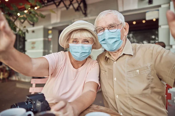 Älteres Paar in Schutzmasken sitzt in einem Café — Stockfoto