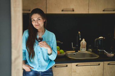 Tezgaha yaslanmış şarap kadehli bir kadın.