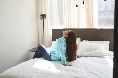 Gözleri kapalı, yatak odasında dinlenen bir kadın.