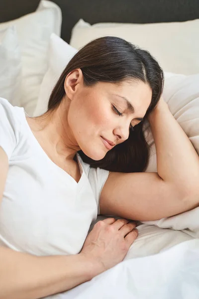 Donkerharige vrouw slaapt vredig in haar slaapkamer — Stockfoto