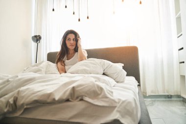 Ciddi üzgün, koyu saçlı, beyaz bir kadın gözlerini dikip bakıyor.