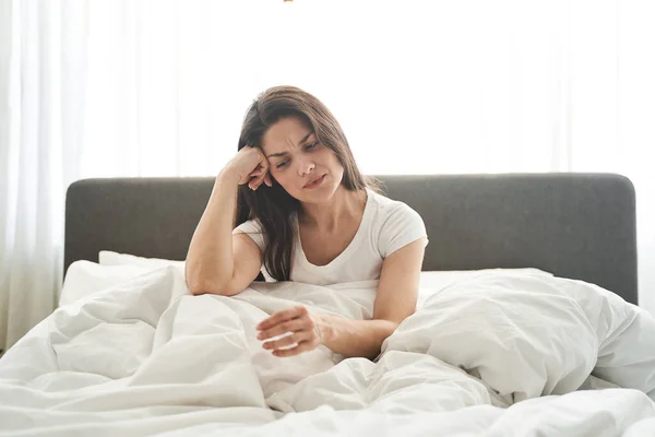 Desesperada joven caucásica sentada en la cama —  Fotos de Stock