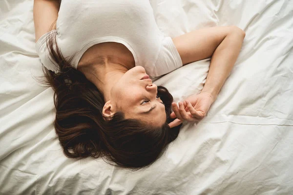 Señora tranquila en una camiseta acostada en la cama — Foto de Stock